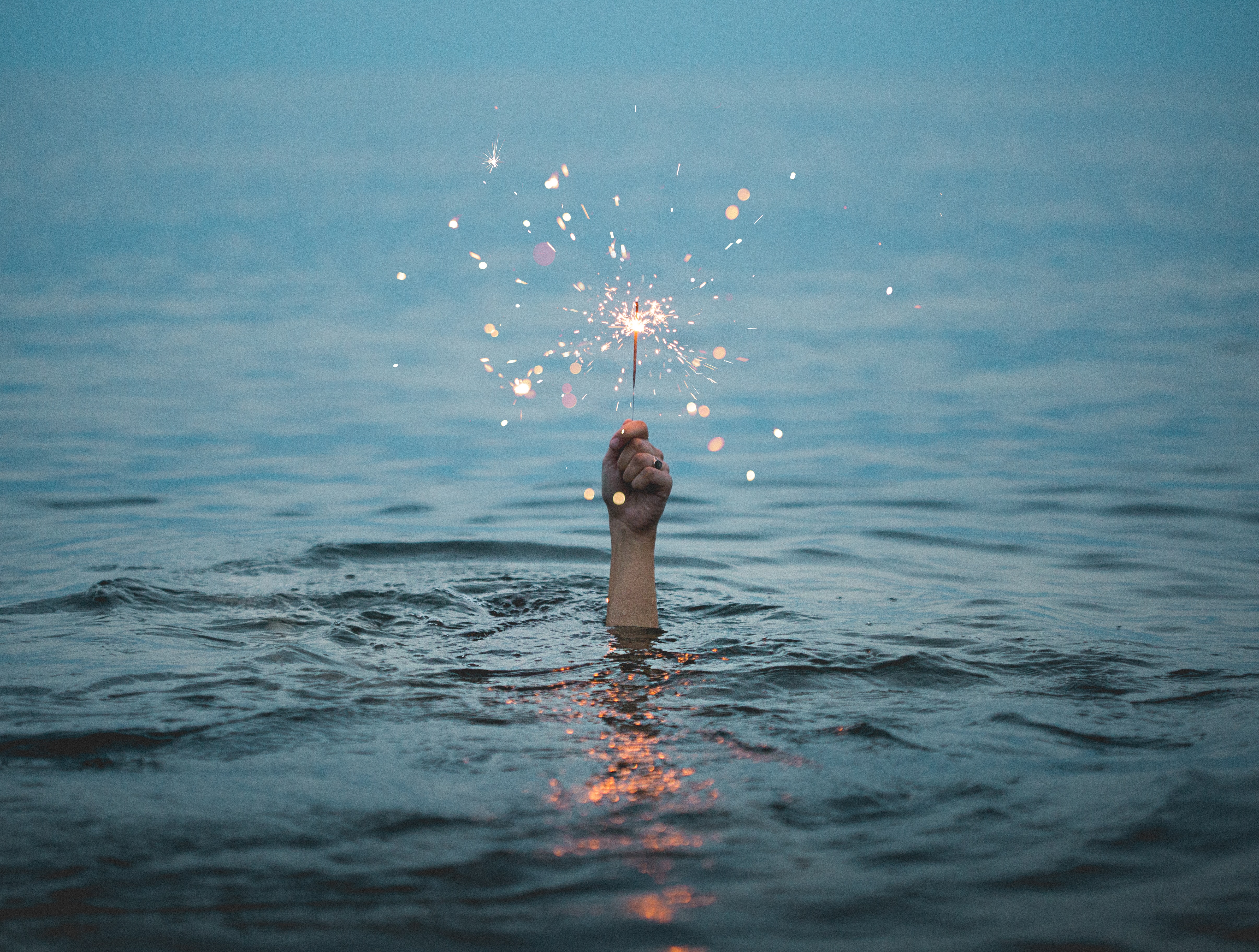 Hand above the water with a sparkler.